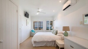 Une chambre à coucher comprenant un lit, une table de chevet, une lampe et une vue sur l’extérieur par la fenêtre.