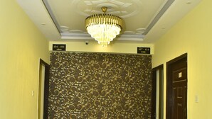 A hallway with a patterned wall, a chandelier, and doors labeled with room numbers. - Magadh Palace  (Danapur)