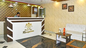 A hotel reception area with a reception desk, a white sofa, and a coffee table. - Magadh Palace  (Danapur)