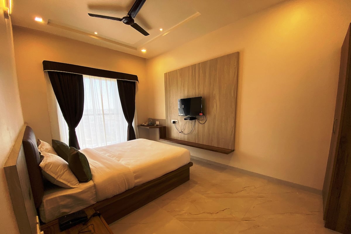 Une chambre d’hôtel moderne dotée d’un grand lit, d’un ventilateur de plafond, d’un téléviseur à écran plat fixé au mur et d’un sol en marbre.
