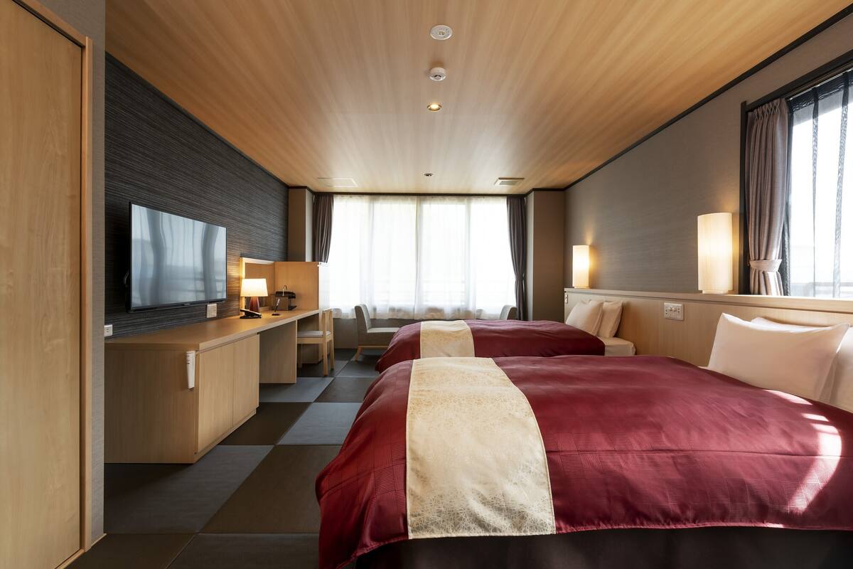 Ein modernes Hotelzimmer mit einem großen Bett, einem Schreibtisch mit Fernseher und einer Sitzecke.