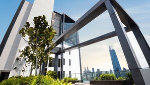 A modern building with a glass facade, large structural beams, and a view of the city skyline. - Continew by Plush (Kuala Lumpur)