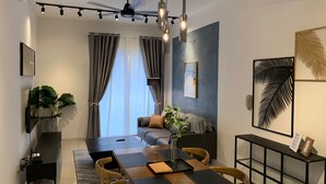 A modern living room with a dining area, a sofa, a coffee table, and a TV mounted on the wall. - Continew by Plush (Kuala Lumpur)