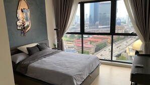 A modern bedroom with a large bed, a city view, and a desk with a lamp. - Continew by Plush (Kuala Lumpur)