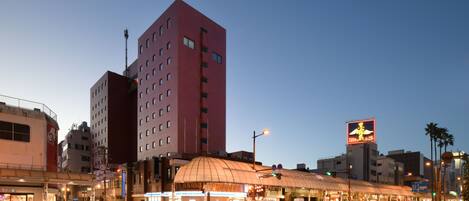 A cityscape with a prominent red building, a covered structure, and a large illuminated sign.