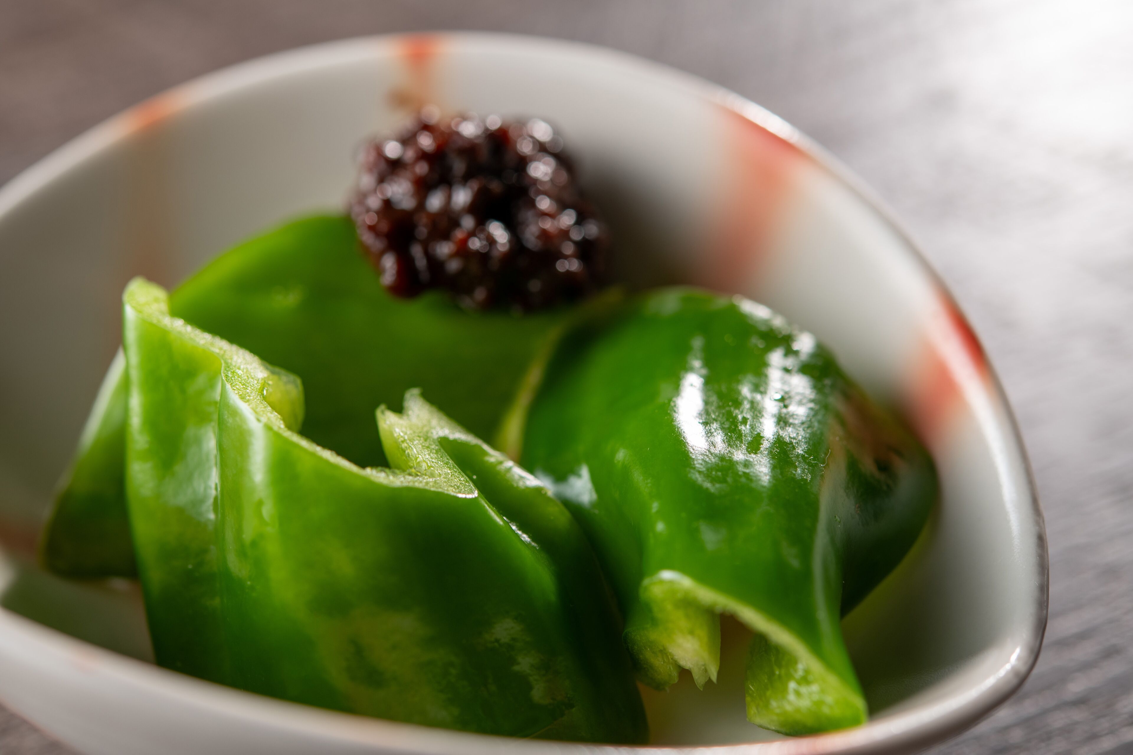 A bowl containing green dumplings and a dark red topping.