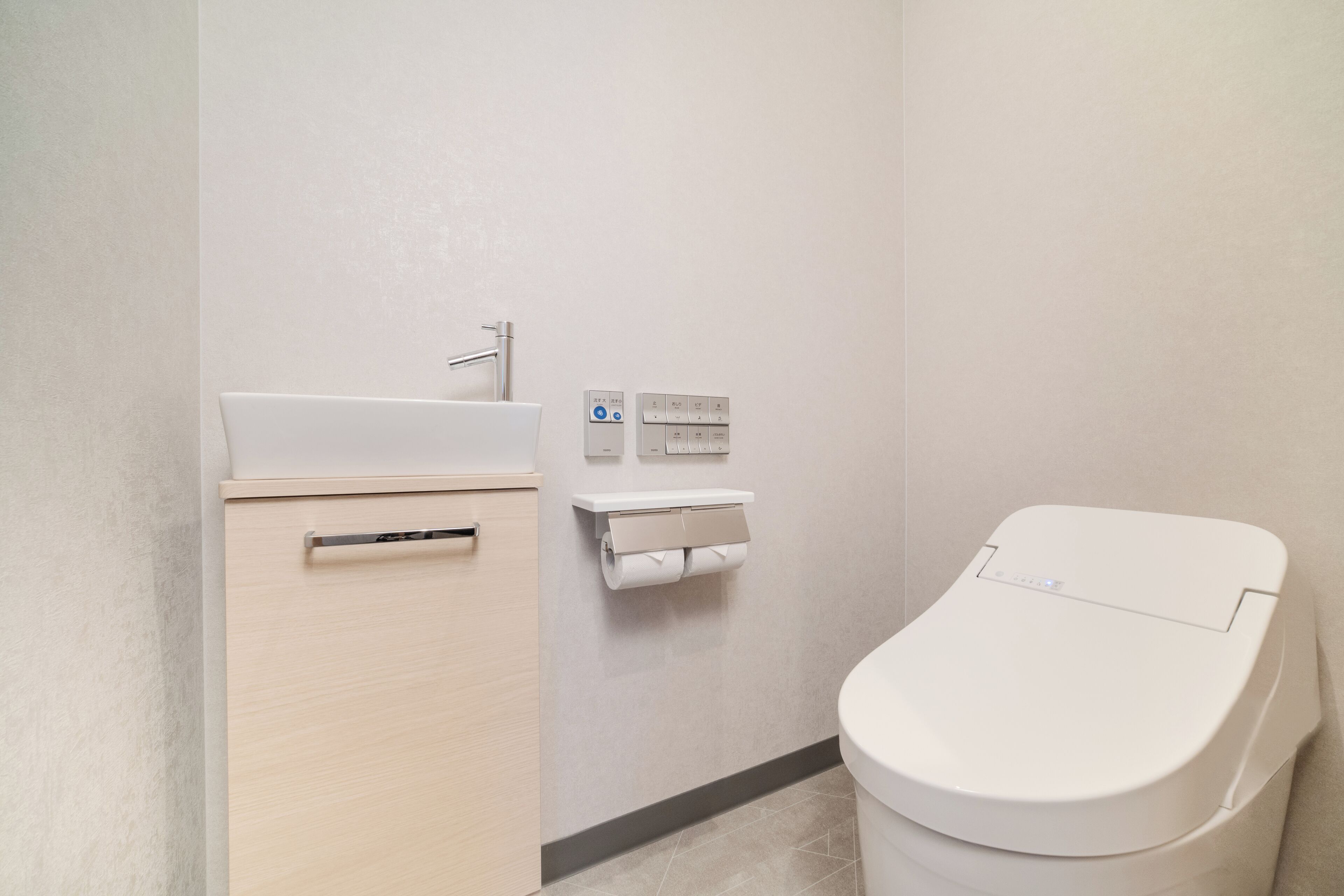 A bathroom with a toilet, a sink, and a toilet paper holder.