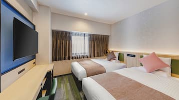 Ein Hotelzimmer mit zwei Betten, einem Flachbildfernseher, einem Schreibtisch und einem fenster mit Vorhängen.