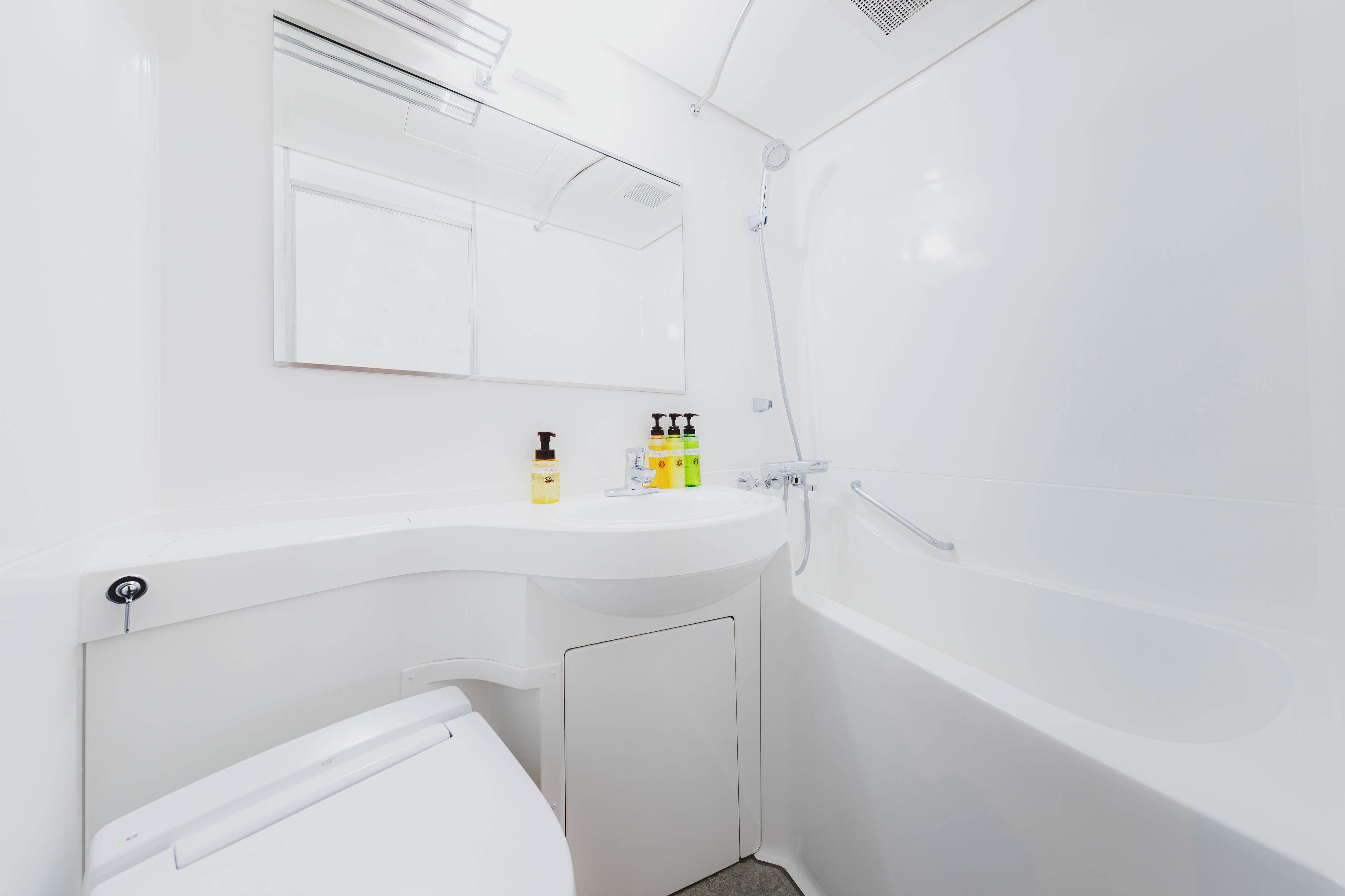 A modern bathroom with a white sink, mirror, and bathtub.