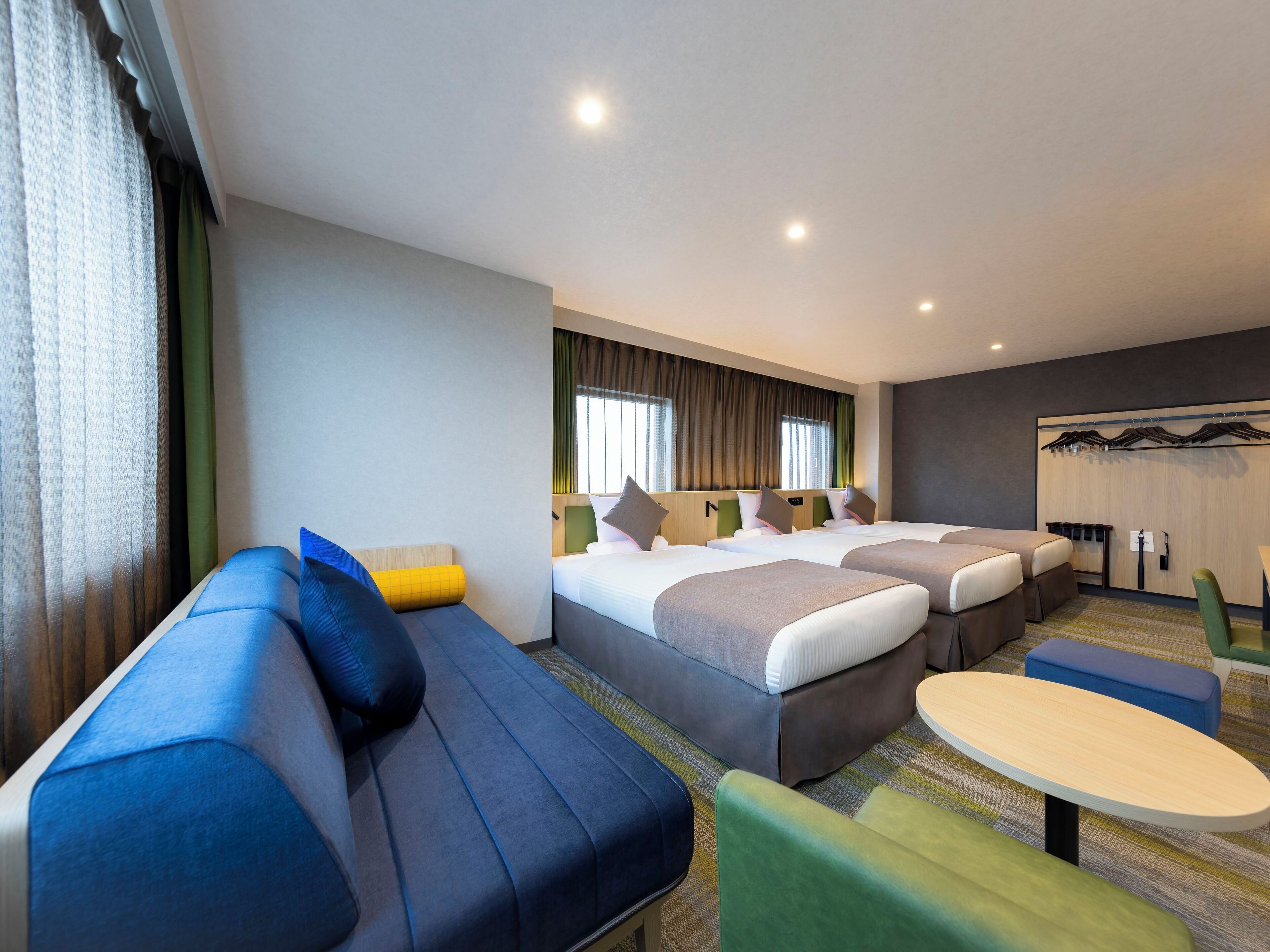 A hotel room with two beds, a sofa, a small table, and a seating area.
