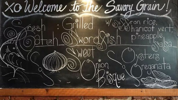 A chalkboard menu with various dishes listed, such as grilled swordfish and oysters, displayed in a restaurant with a brick wall background. - * Prime Location: 2-BR Oasis with Washer & Dryer * (Richmond)