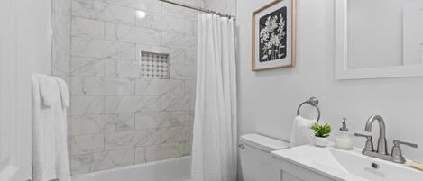 A modern bathroom with a bathtub, toilet, and sink.
