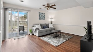 A modern living room with a grey sofa, a coffee table, a ceiling fan, and a TV on a stand. - Inviting Retreat: Spacious 2 BR 1.5 Bath Townhouse (Hopewell)