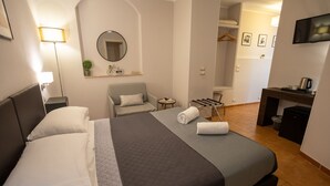 A hotel room with a large bed, a desk, a chair, a mirror, and a television. - Helios Assisi (Assisi)