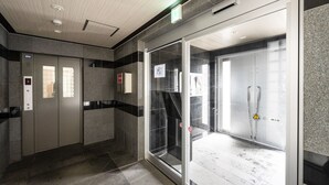 Un área de ascensor moderna con puertas de vidrio, un panel de control y un letrero de seguridad.