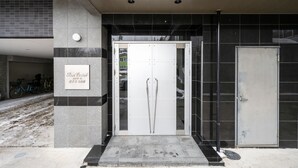 Entrada de un edificio con puerta de vidrio, un cartel y una bicicleta estacionada afuera.