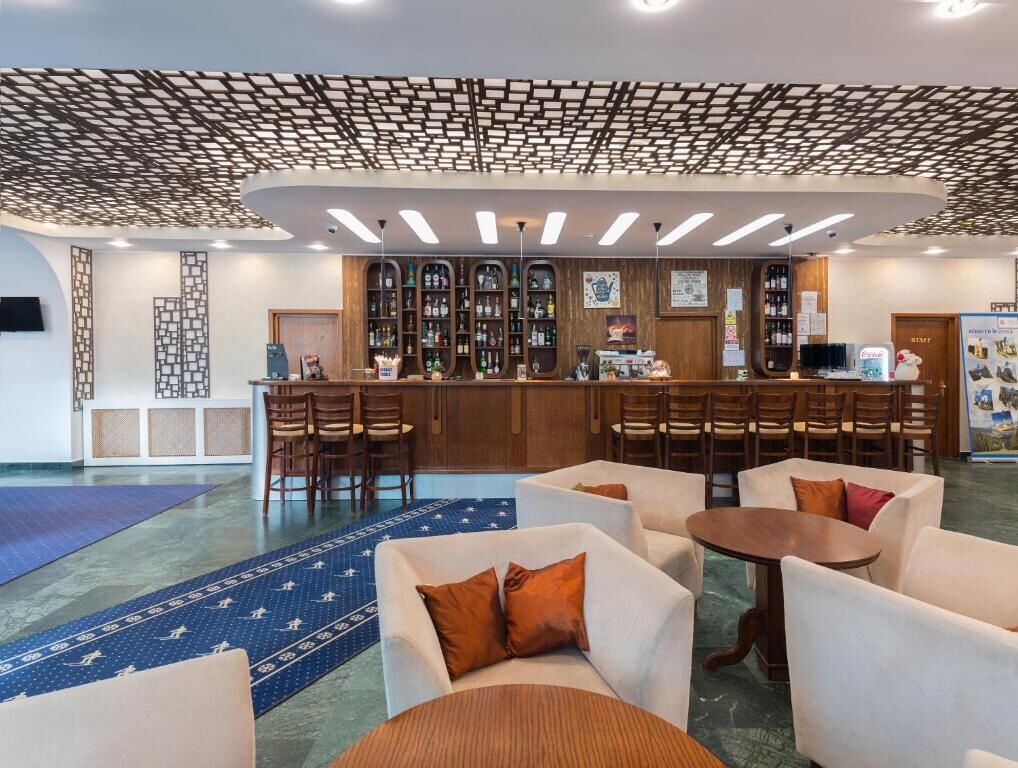 Un hall con mostrador de recepción, zona de estar y bar con estantes llenos de botellas.