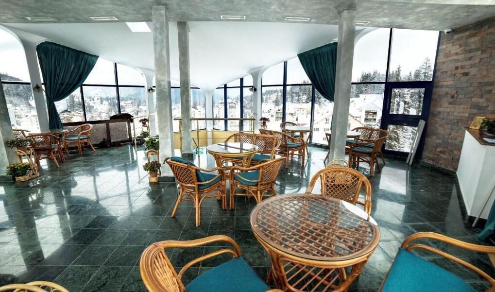 A spacious indoor area with wicker furniture and large windows offering a view of a snowy landscape.