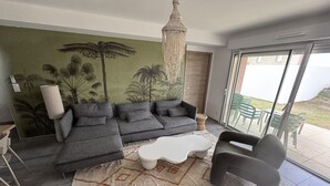 A modern living room with a sectional sofa, a white coffee table, and a large window with a view of the outdoors.