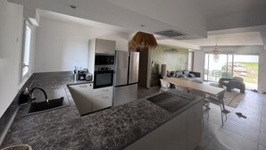 A modern kitchen with a central island, built-in appliances, and a dining area with a view.