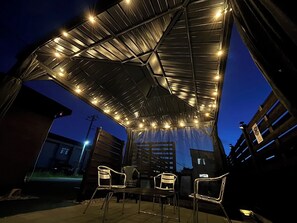 An outdoor patio area with a covered seating area, chairs, and a table.