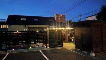 A building with a gated entrance, a parking area, and a small adjacent structure.