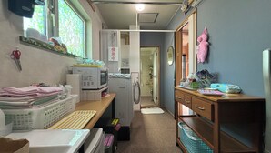 A laundry room with a washing machine, dryer, and stacked towels. - Guest House MOMO (Obihiro)