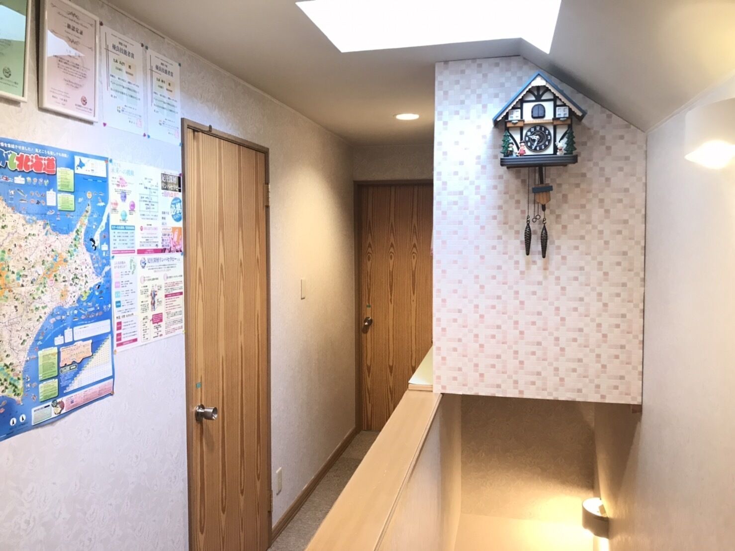 A hallway with a wooden door, a map on the wall, and a cuckoo clock.
