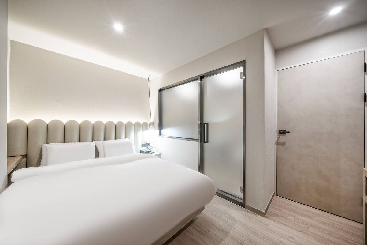 Een moderne hotelkamer met een groot bed, een garderobe en een nachtkastje.