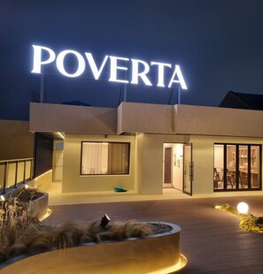 Ein Gebäude mit einer großen, beleuchteten Schrifttafel mit der Aufschrift „POVERTA“.