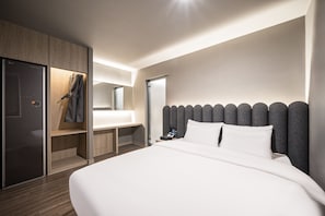 A modern hotel room with a large bed, a wooden wardrobe, a vanity with a mirror, and a nightstand with a phone. - POVERTA STAY HOTEL (Gyeongju)