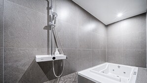 A modern bathroom with a shower, a bathtub, and grey tiled walls.