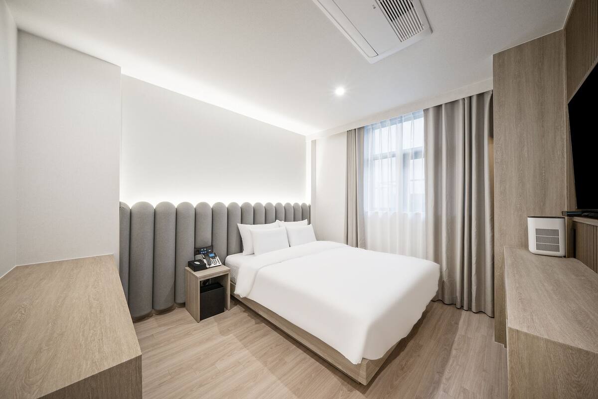 Een moderne hotelkamer met een groot bed, een nachtkastje en een ingebouwde televisie.
