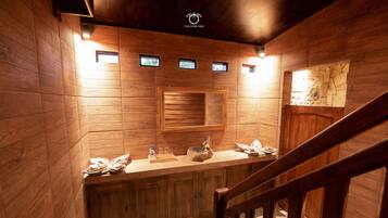 A wooden interior with a stone floor, wooden cabinets, a sink, and a small window.