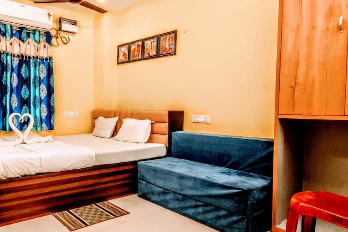 Um quarto com uma cama, um sofá azul, uma cadeira vermelha e um armário de madeira.