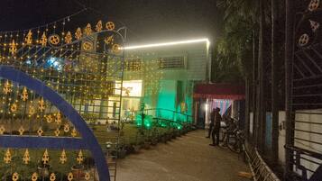 A nighttime outdoor area with decorative lights, a pathway, and a building with a red awning.