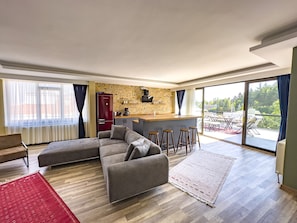 Relax in a spacious living area with a large L-shaped sofa and matching ottoman, adjacent to a kitchen with an island and bar stools.