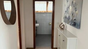 A hallway with wooden flooring, a white cabinet with drawers, a mirror, and a painting on the wall. - Apartment mit Bergblick (Aldrans)
