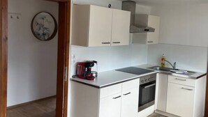 A modern kitchen with white cabinets, a built-in oven, and a coffee maker on the countertop. - Apartment mit Bergblick (Aldrans)