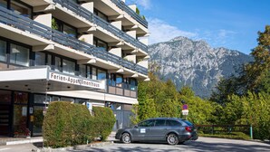 Een hotel met een bord waarop 'Ferien-Appartementhaus' staat, een auto ervoor geparkeerd en een berg op de achtergrond.