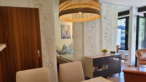 Een moderne woonkamer met een eetgedeelte, een bank, een salontafel en een hanglamp van riet.
