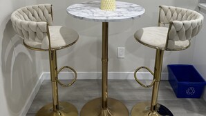 A round table with a vase of feathers, two tufted chairs, and a blue recycling bin. - Brand new 2 bdrm 3 beds luxury Guest Suite with separate entrance (Calgary)