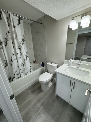 A modern bathroom with a bathtub, toilet, and sink.