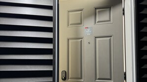 A door with a keypad lock, a peephole, and a sign indicating it is a registered secondary unit. - Brand new 2 bdrm 3 beds luxury Guest Suite with separate entrance (Calgary)