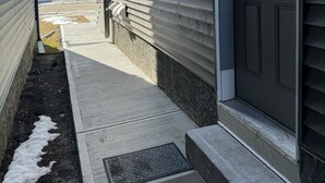 A residential building with a garage door, a small outdoor area with steps, and a clear sky. - Brand new 2 bdrm 3 beds luxury Guest Suite with separate entrance (Calgary)