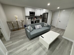 A modern kitchen with white cabinets, a microwave, and a refrigerator.
