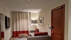 A modern living room with a sofa, a coffee table, and a TV mounted on the wall. - Bladi Suite Oran (Oran)