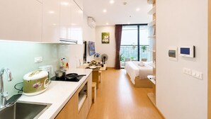 Een moderne keuken met een spoelbak, fornuis en een eethoek. Een slaapkamer met een bed en een balkon met planten.