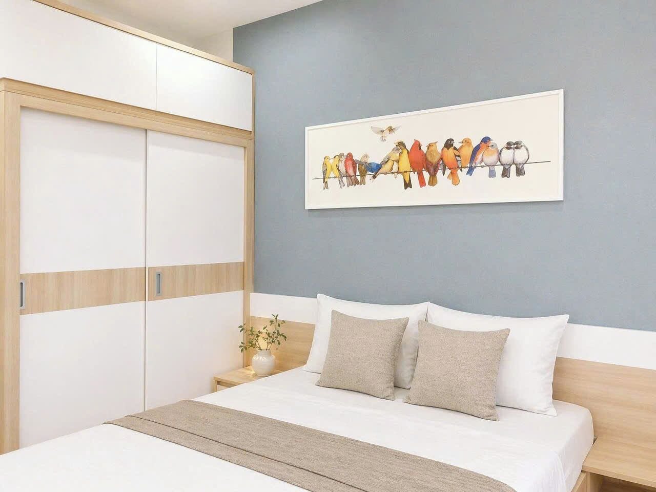 Un dormitorio con una cama, una mesita de noche, una obra de arte en la pared con pájaros y un armario.