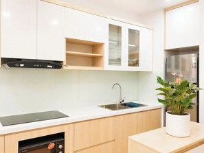 A modern kitchen with white cabinets, a stainless steel refrigerator, a dishwasher, and a sink.